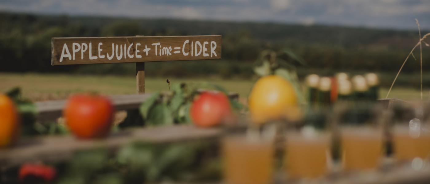 Skylt på landsbygd med texten "Apple juice + time = cider"